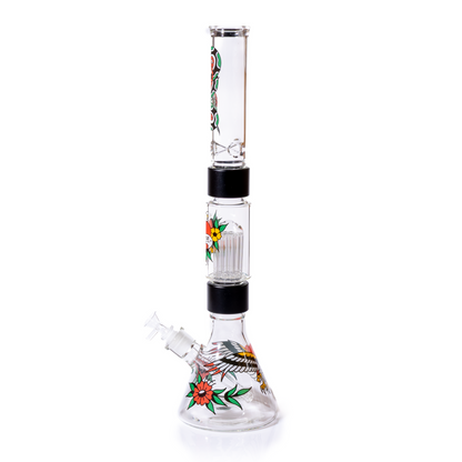 Side view of the Prism Inked double stack beaker with the 14mm female glass joint angled left.  The large tree percolator chamber stacked above the beaker has an an ed hardy style heart on it with the Prism logo. Decal decorations include the Prism heart, eagle and the snake tattoos. This assembly uses precision-machined aluminum fittings for simple maintenance and maximum durability. The easiest percolated bong to clean. 