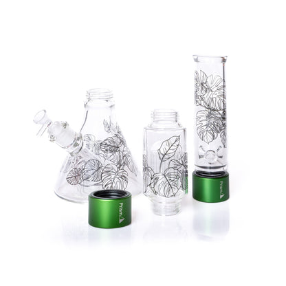 Set of glass smoking accessories with leaf designs and green bases on a white background